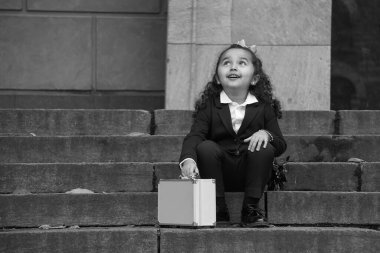 A girl sits on the steps outside a building clipart