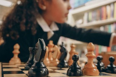 Bir kız kütüphanede satranç oynuyor.