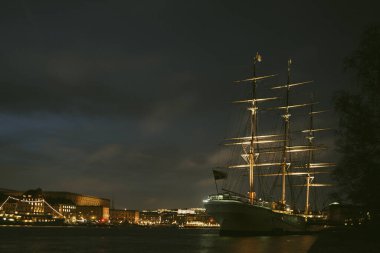 Arka planda şehir olan bir gemi demirlemiş.