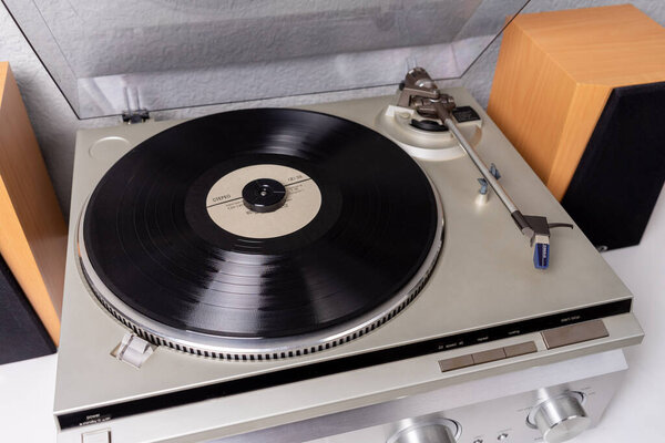 vintage vinyl player with amplifier and loudspeakers on white table