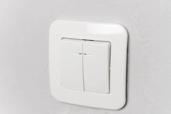グレーの壁に白いプラスチックライトスイッチ — ストック写真