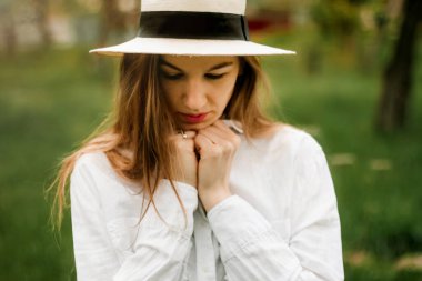 Meyve bahçesinde açık renk elbiseli, uzun sarı saçlı güzel bir kadın.