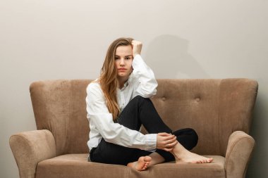 Bej bir kanepede oturan uzun saçlı güzel genç bir kadın.