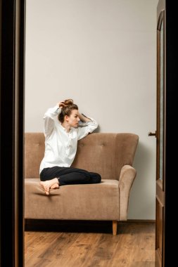 Bej bir kanepede oturan uzun saçlı güzel genç bir kadın.