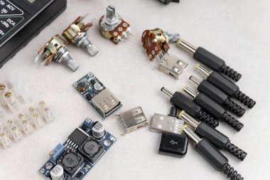 Gri arka planda farklı elektrikli aletlerin düzenlenmesi. çokölçer, dönüştürücü, adaptörler, ısı küçültücü vs..