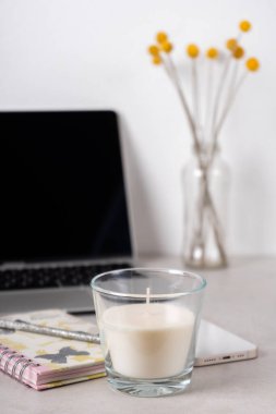 Kadınların çalışma alanı, dizüstü bilgisayar, telefon, çiçekler, mum ve yapılacaklar listesi 
