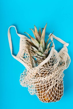 Mavi arka planda bej bir sicim torbasında ananas