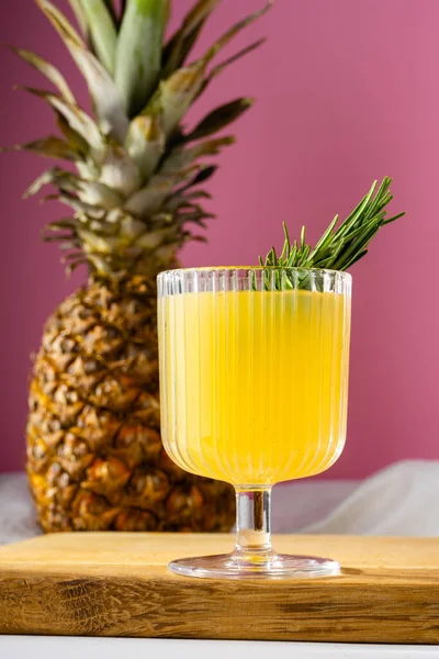 stock image side view of a glass of pineapple juice and a pineapple on bright pink background