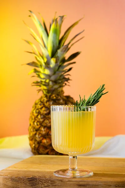 Bir bardak ananas suyu ve ananasın yan görüntüsü.