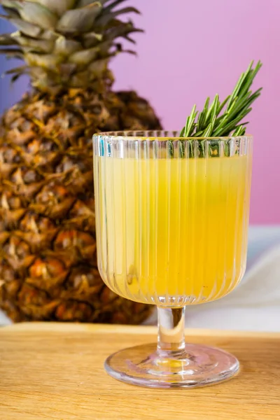 stock image side view of a glass of pineapple juice and a pineapple on bright pink background