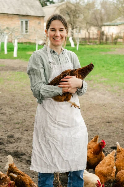 Elinde tavukla kameraya gülümseyen çekici bir genç kadın.