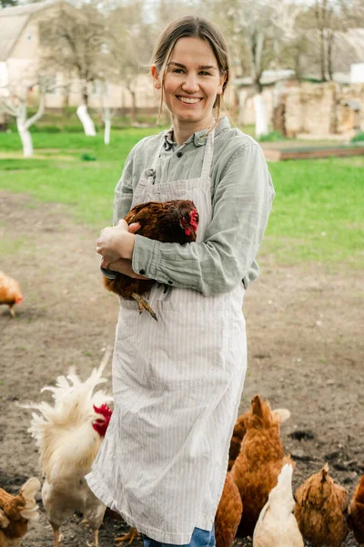 Elinde tavukla kameraya gülümseyen çekici bir genç kadın.