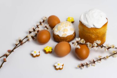 Beyaz arka planda yumurta ve çiçek açan dallı Paskalya pastaları.