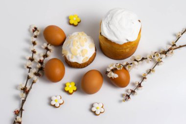 Beyaz arka planda yumurta ve çiçek açan dallı Paskalya pastaları.
