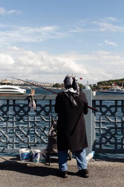 İstanbul 'daki Galata Köprüsü' nde tanınmayan bir balıkçının görüntüsü. Görüntü, yerel halkın yaşam tarzını ve kültürünü yansıtıyor. Güneşli bir yaz günü..
