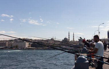 İstanbul 'un Galata Köprüsü ve Eminonu bölgesindeki balıkçılar görülüyor. Görüntü, yerel halkın yaşam tarzını ve kültürünü yansıtıyor. Güneşli bir yaz günü..