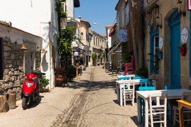 View of a narrow street and old, historical, traditional stone houses in famous, touristic Aegean town called Alacati. It is a village of Cesme, Turkey. It is a sunny summer day