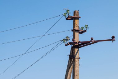 Mavi gökyüzünün arka planında yakın plan elektrik hatları var. Direkte elektrik merkezi. Gökyüzünde yüksek voltaj kabloları var. Acil durum ışıkları söndü. Ukrayna 'nın enerji sisteminin yok edilmesi