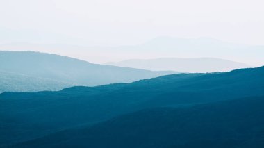 Görünür siluetlerle sabah sisli dağlarda. Gün batımında dağlarda sakin bir akşam manzarası. Resim duvar kağıtları. Doğal arka plan. Panorama. Kırım, Ukrayna.