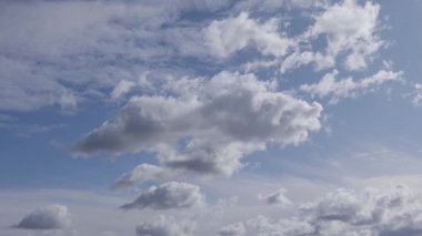White fluffy clouds moving fast against blue sky. Amazing cloudscape at sunny day. Picturesque nature landscape with clouds
