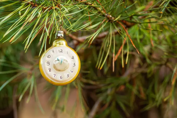 Yeni yıl saati ve köknar dalları şeklinde bir Noel ağacı oyuncağı. Yılbaşından beş dakika önce. Süslemeli Noel arkaplanı.