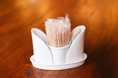 Ahşap bir masanın üzerinde bir sürü kürdanı olan bir tutucu, yakın plan. Kürdanları masaya koyun..