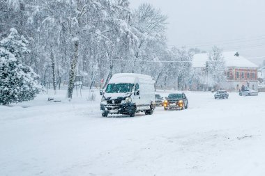 Kışın yoğun bir kar yağışı sırasında şehir caddesinde kaygan bir yolda giden arabalar. Kar fırtınaları ve kar fırtınaları nedeniyle trafik aksaması. Hava tahminleri.