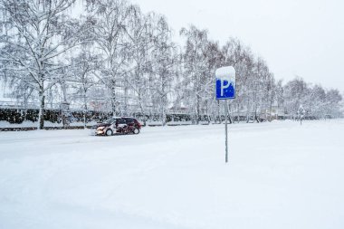 Yol işareti park ettiğini gösteriyor. Bir kış günü kar yağışı sırasında karlı bir caddede yol tabelası. Karla kaplı caddeye park ediyorum.