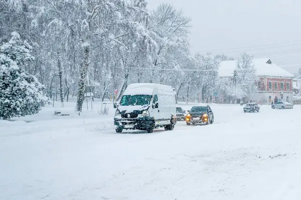 Kışın yoğun bir kar yağışı sırasında şehir caddesinde kaygan bir yolda giden arabalar. Kar fırtınaları ve kar fırtınaları nedeniyle trafik aksaması. Hava tahminleri.