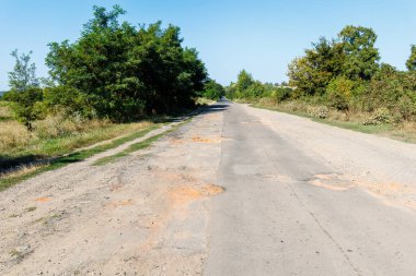 Kötü yol, asfalt çatlamış çukurlar ve büyük delikler. Asfalt yüzeyi yolda yok oldu. Yolun kötü durumda, onarılması gerekiyor.