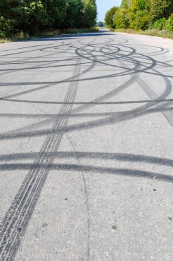 Yol yüzeyinde fren izleri var. Donut yapan sürücülerin bıraktığı dairesel lastik izleri. Asfalt yolda lastik izi.