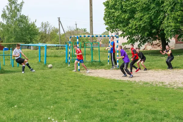 stock image May 16, 2023, Romny, Ukraine: Teenage boys play street soccer on the lawn of a summer sports ground in the middle of greenery. Live emotions on the faces and the ball in the game