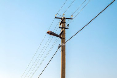 Mavi gökyüzünün arka planında yakın plan elektrik hatları var. Direkte elektrik merkezi. Gökyüzünde yüksek voltaj kabloları var. Acil durum ışıkları söndü. Ukrayna 'nın enerji sisteminin yok edilmesi.