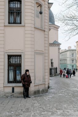 Lviv, Ukrayna, 8 Ocak 2015: Uzun beyaz sakallı, fakir elbiseli, yaşlı, evsiz bir adam kaldırımda dururken insanlardan para istiyor. Yoksulluk ve umutsuzluk kavramı