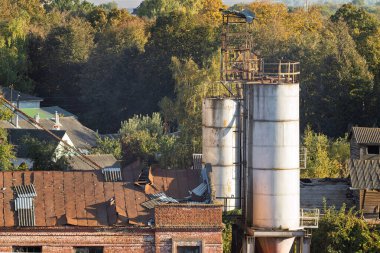 Paslı çatısı ve çürümüş yapısı olan terk edilmiş eski bir sanayi binası. Çarşaflar çatıya saçılmış, harap durumdaki durumu vurguluyorlar..