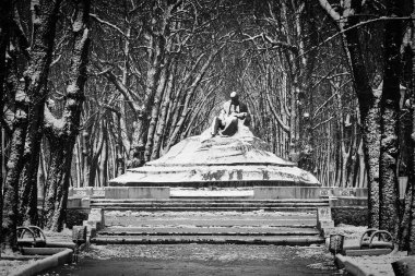 Monument to T. G. Shevchenko in winter, surrounded by snow-covered trees and stairs in the city of Romny, Sumy region, Ukraine. clipart