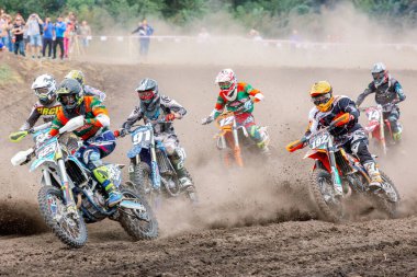 Ukrayna, Romny şehri, Eylül 05-06, 2020: Motokros yarışçıları izleyicilerle çevrili bir toprak pistte yarışıyorlar. Açık hava spor fotoğrafçılığı aksiyon ve hareketi yakalıyor.