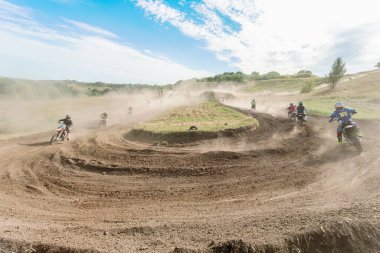 Ukrayna, Romny, 5-6 Eylül 2020: Dar virajlarda ve engebeli arazide hareket eden motorcularla dinamik motokros yarışı, açık arazi ve parlak gökyüzü altında toz bulutları.