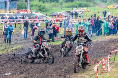 Ukrayna, Romny, 2-3 Haziran 2018: Genç motokros yarışmacıları, Ukrayna Motokros Şampiyonası sırasında etrafı izleyicilerle çevrili bir çim pistinde yarışıyor.