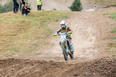 Ukrayna, Romny, 5-6 Eylül 2020: Motokros yarışçısı arka planda seyircilerle toprak pistte yarışıyor. Dinamik spor görüntüleri hız ve aksiyon gösteriyor. Ukrayna Motokros Şampiyonası