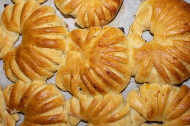 Karmaşık kesikli altın kahverengi hamur işleri, yeni pişmiş ve parşömen kağıdına serilmiş. Üst aşağı görünüm ayrıntılı dokularını ve yumuşak kabuklarını gösterir