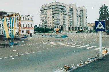 June 25, 2000, Romny, Ukraine: City Square, covered with garbage and garbage after a public gathering or festival, with abandoned structures, flags and pedestrian marks. clipart