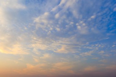 The morning sky with soft scattered clouds. The sky has a gradient from warm pale yellow below to cool light blue above. Cloud formations are soft and thin clipart