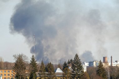 Şehir merkezinin üstündeki kara duman gökyüzüne yükseliyor. Yangın, endüstriyel kaza ya da patlama olabilir. Sahne aciliyet ve kriz gösteriyor.