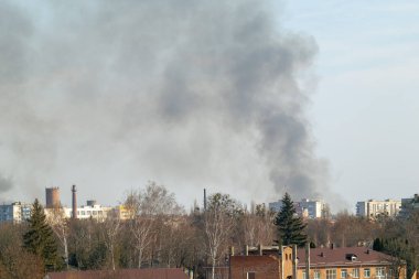 Şehir merkezinin üstündeki kara duman gökyüzüne yükseliyor. Yangın, endüstriyel kaza ya da patlama olabilir. Sahne aciliyet ve kriz gösteriyor.