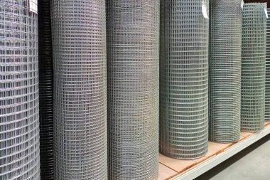 Endüstriyel tel örgüler düzgün bir şekilde bir depodaki raflara yerleştirilmiş. İnşaat ve eskrim amaçlı düzen ve organizasyonun özünü yakalıyorlar.