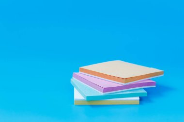 Parlak mavi arkaplan üzerine yerleştirilmiş pastel kare kağıtlar, verimlilik, planlama ve ofis kullanımı için ideal.