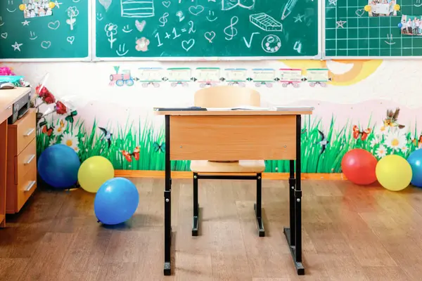 Süslü bir masası, balonları ve karatahtası olan oyuncu ve misafirperver bir ilkokul. Yeni bir okul yılı ve erken gelişim için hazır..