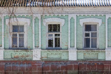 Üç yıpranmış ahşap çerçeveli pencerenin ön görüntüsü dekoratif yeşil ve beyaz tuğlalı bir duvarın boyası soyuluyor..