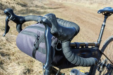 Çakıl motosikletlerinin yakın çekimi engebeli toprak bir yolda gidonları ve gidonu düşürür. Macera bisikleti ve bisiklet paketlerini gösterir.